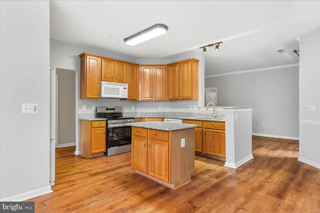 a kitchen with stainless steel appliances granite countertop a sink cabinets and wooden floor