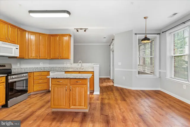 a kitchen with stainless steel appliances granite countertop a sink a stove a refrigerator cabinets and wooden floor