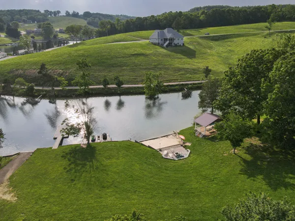 a view of a lake with a yard and large trees