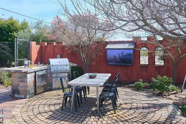 a backyard of a house with barbeque oven table and chairs