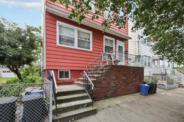 a view of a house with a small yard and large tree