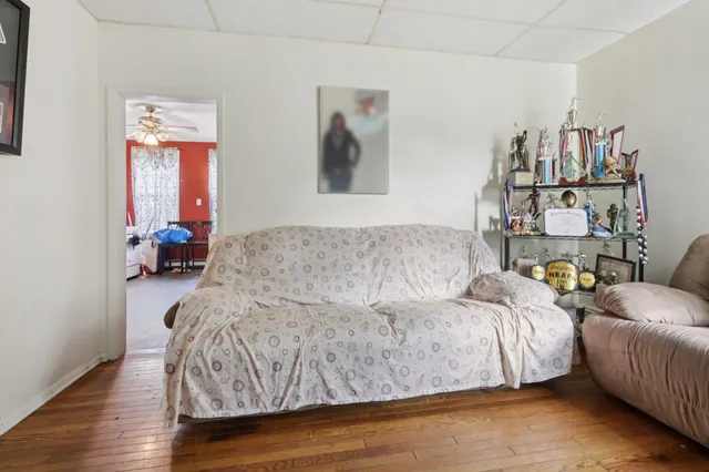 a living room with a bed and wooden floor