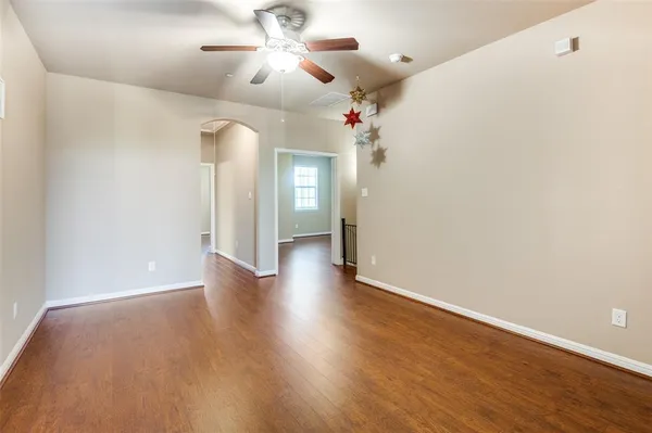 wooden floor in an empty room with a chandelier fan