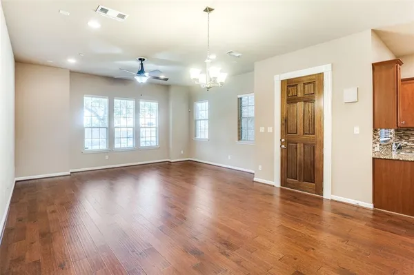 a view of an empty room with window and wooden floor
