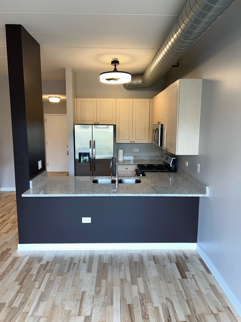 1155 West Madison Street, Unit 305 Chicago, IL 60607 - Photo 3 of 7 a living room with wooden floor and kitchen view