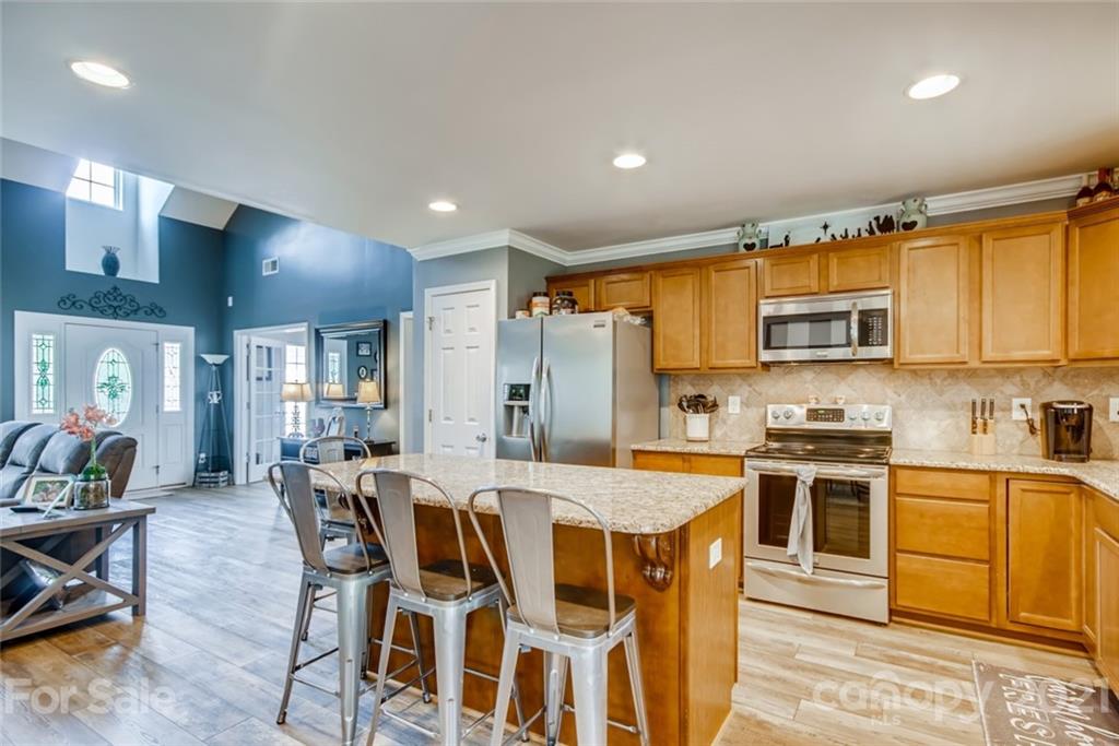 1682 Lane Road Mount Holly, NC 28120 - Photo 10 of 23 a kitchen with stainless steel appliances granite countertop a stove top oven a sink dishwasher a dining table and chairs with wooden floor