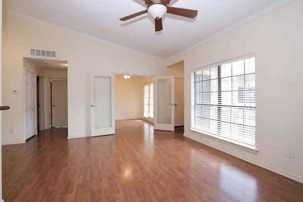 a view of an empty room with wooden floor and a window