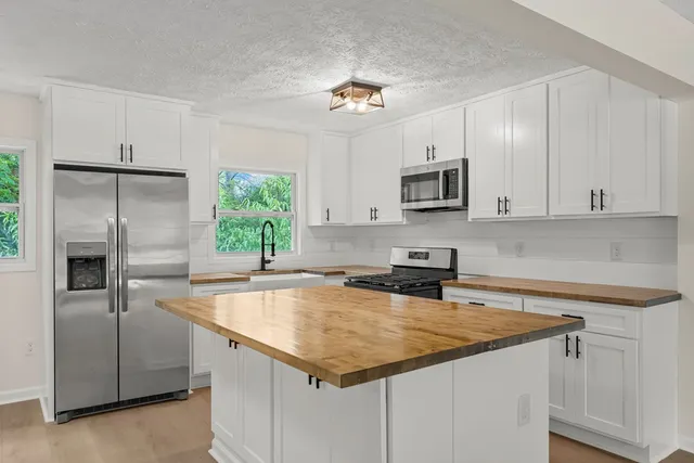 a kitchen with kitchen island granite countertop a sink stove and refrigerator