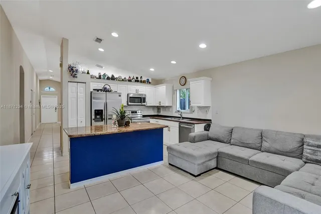 a living room with stainless steel appliances kitchen island granite countertop a couch and cabinets