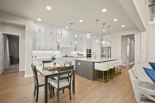 a kitchen with a dining table chairs wooden floor cabinets and stainless steel appliances