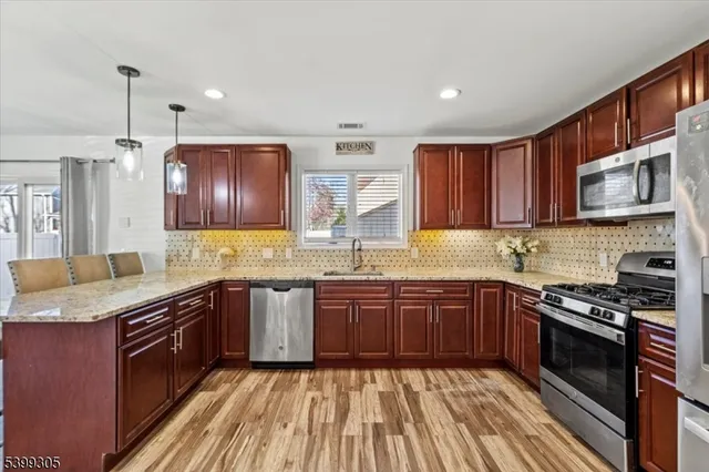 a kitchen with stainless steel appliances granite countertop wooden cabinets sink stove and microwave