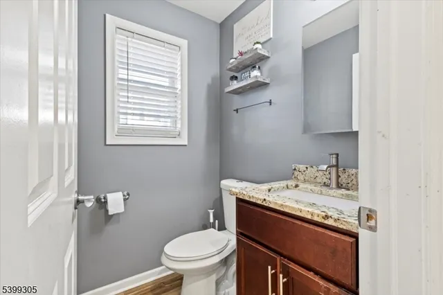a bathroom with a granite countertop sink toilet and mirror