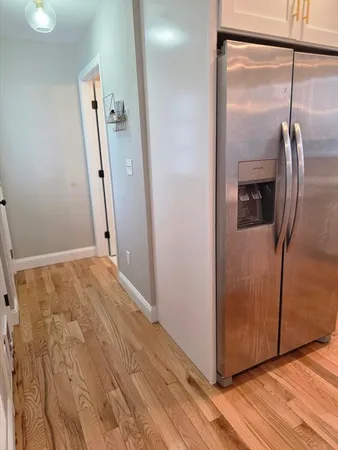 a view of a hallway with wooden floor and a bathroom