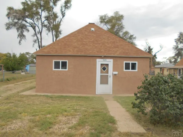 a front view of house with yard and trees around