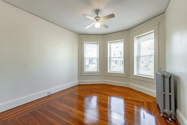 a view of empty room with wooden floor and fan