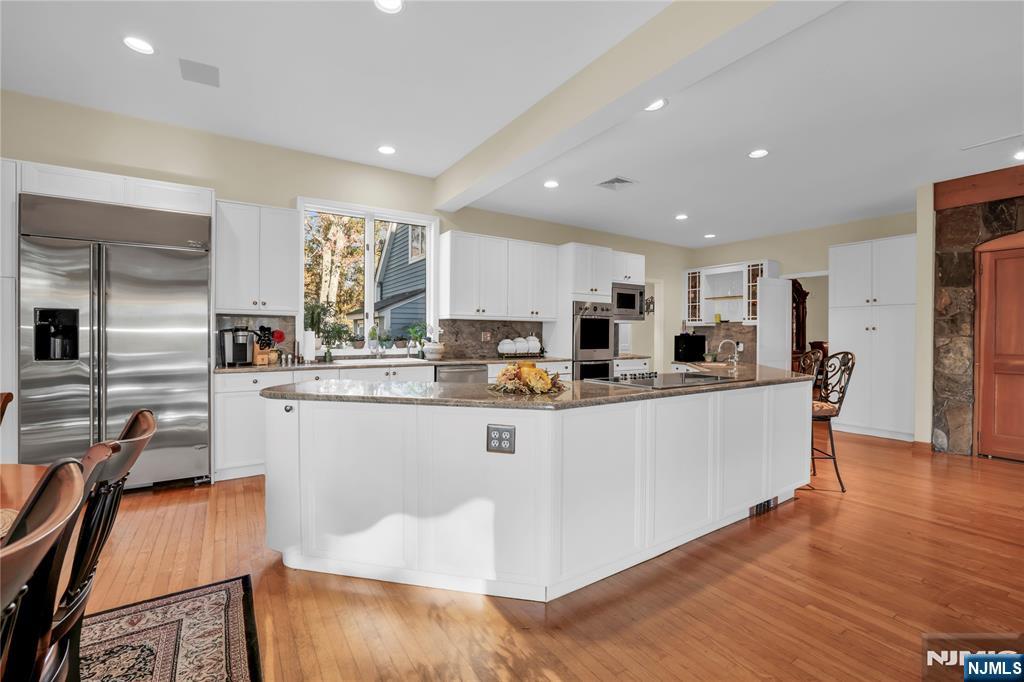 738 Ridge Road Butler, NJ 07405 - Photo 24 of 50 a large kitchen with stainless steel appliances granite countertop a large stove a sink a refrigerator and white cabinets with wooden floor