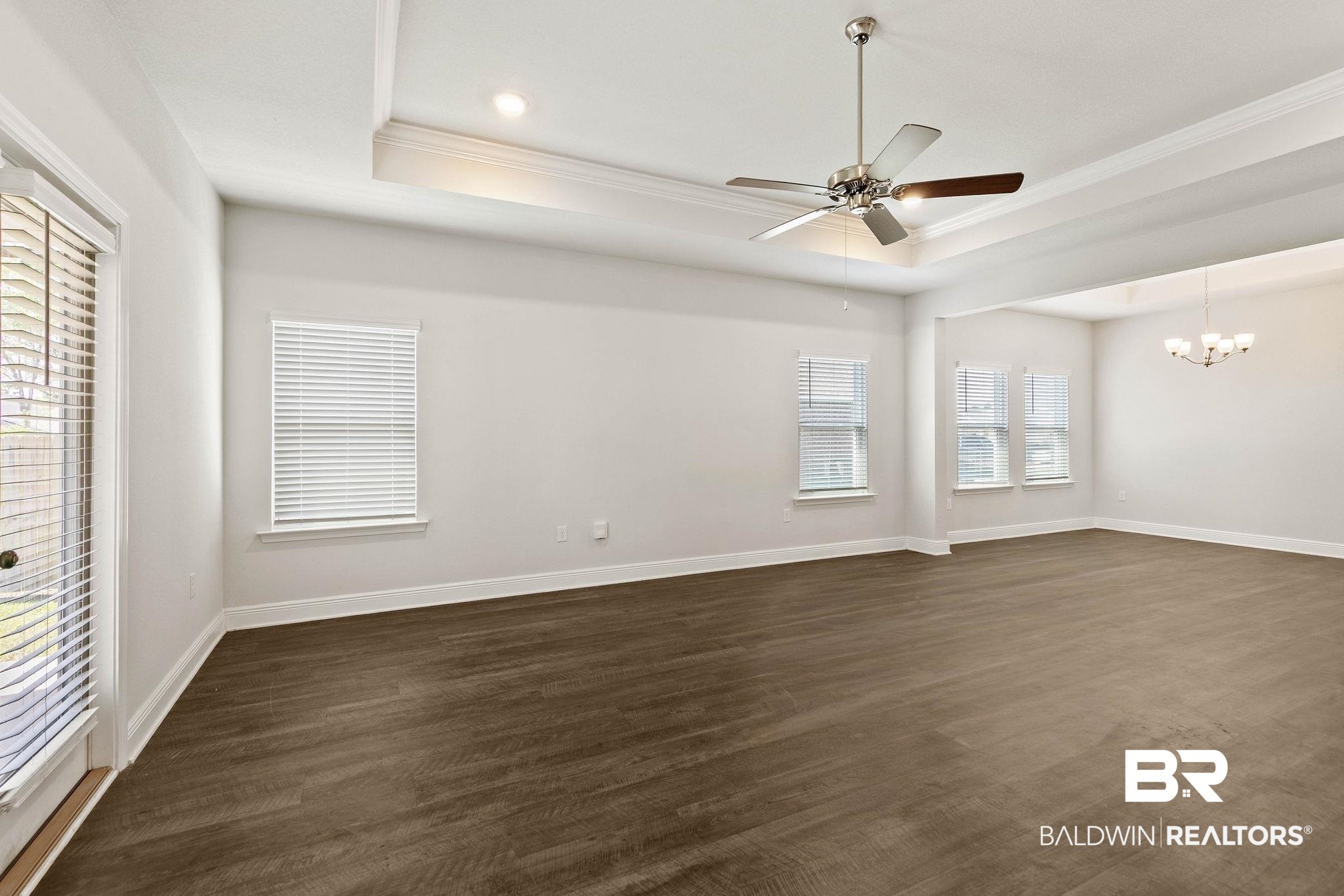 9448 Amethyst Drive Daphne, AL 36526 - Photo 10 of 61 Spare room featuring a ceiling fan, dark wood-style flooring, ornamental molding, suspended lighting, and a tray ceiling