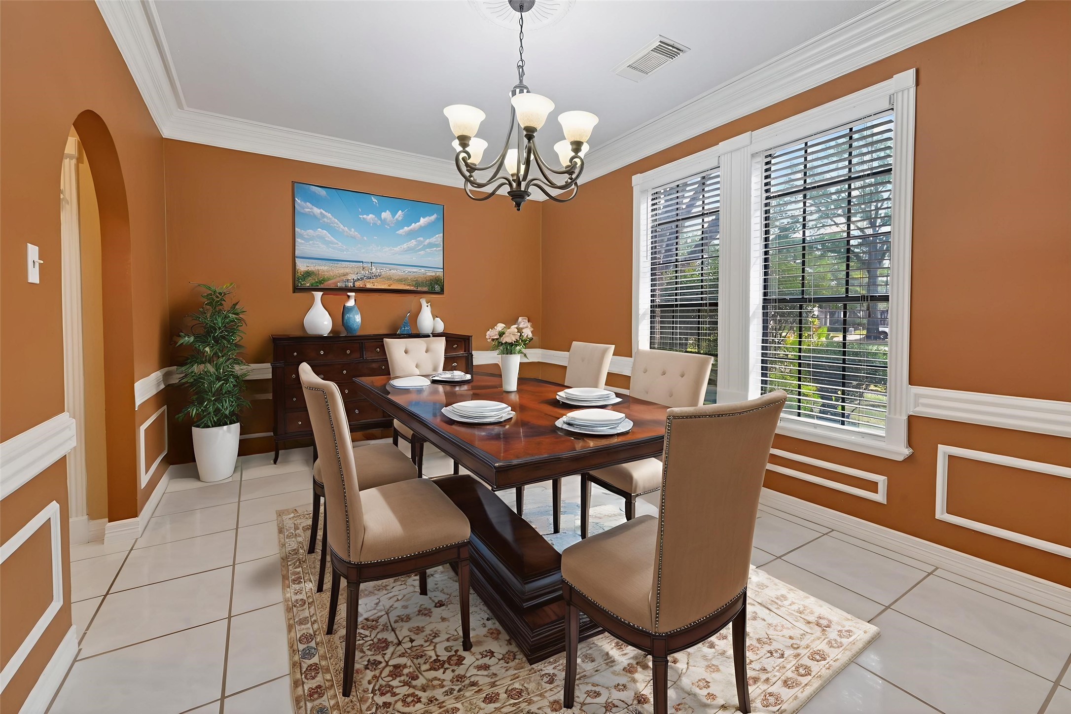 5802 Ashmere Lane Spring, TX 77379 - Photo 13 of 41 This dining room features a warm color palette with rich brown walls and white trim. It includes a large window providing ample natural light, a classic chandelier, and a wooden dining table with upholstered chairs. Elegant decor and tile flooring complete the inviting space.