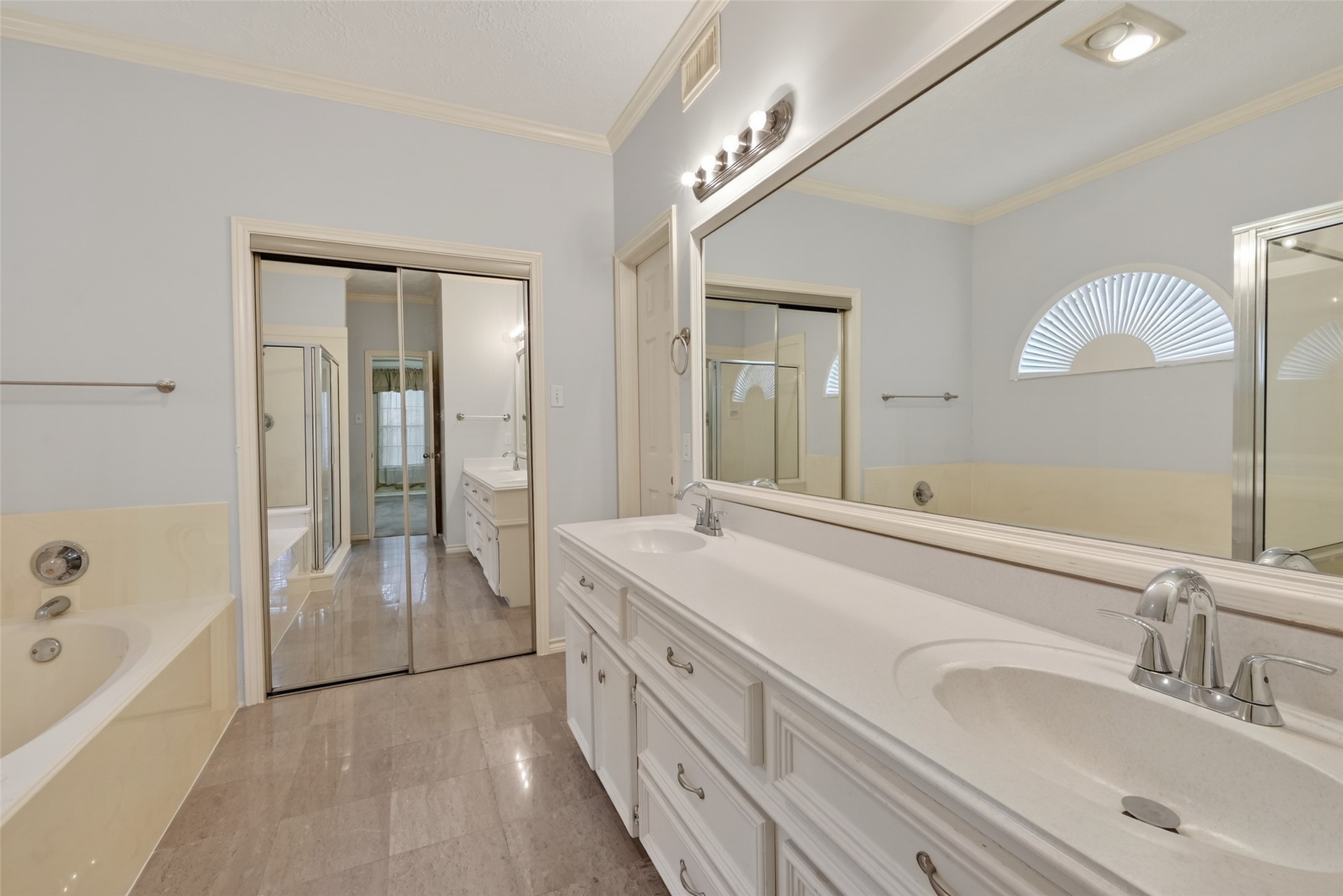 5802 Ashmere Lane Spring, TX 77379 - Photo 18 of 41 This spacious bathroom features a double vanity with ample storage, a large mirror, and modern lighting. It includes a bathtub, a separate shower, and a closet with mirrored sliding doors, offering a bright and functional space.