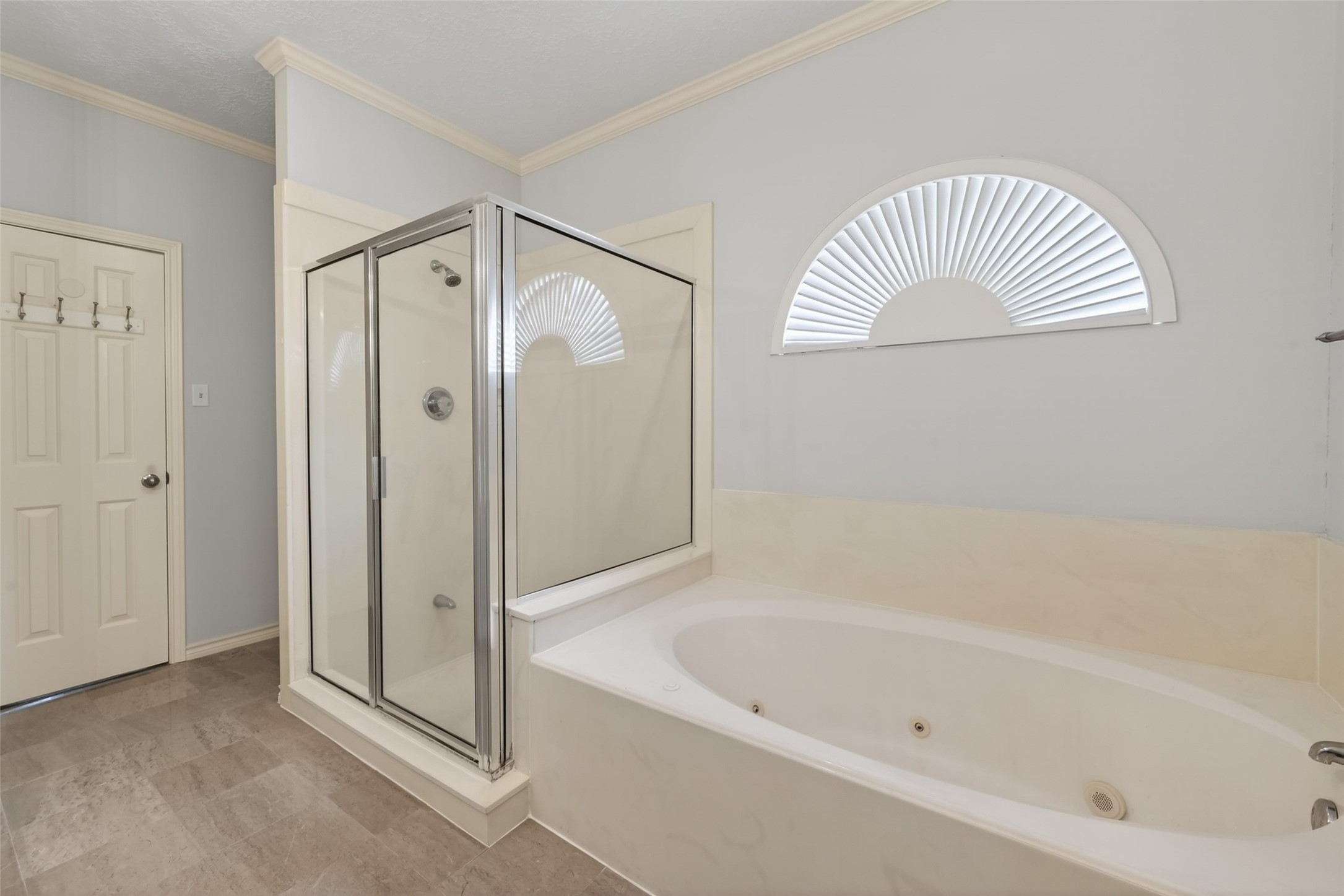 5802 Ashmere Lane Spring, TX 77379 - Photo 20 of 41 This bathroom features a sleek glass-enclosed shower and a large jetted bathtub. The room has neutral tones, a decorative arched window, and modern fixtures, creating a clean and inviting space.