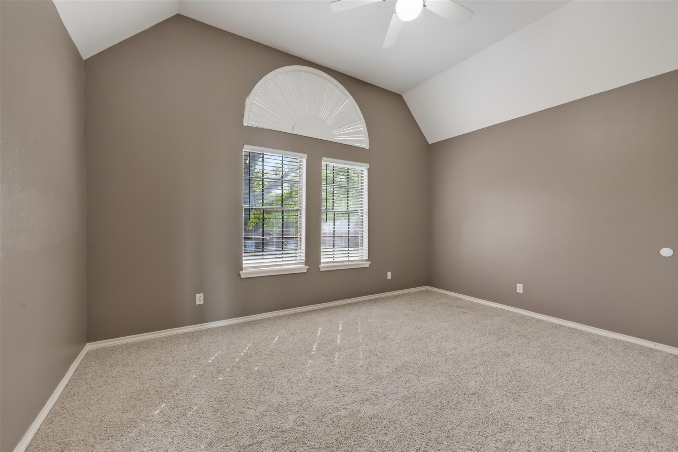 5802 Ashmere Lane Spring, TX 77379 - Photo 27 of 41 This room features a vaulted ceiling with a fan, neutral carpet, and walls. It has a large window with an arched transom, providing ample natural light.