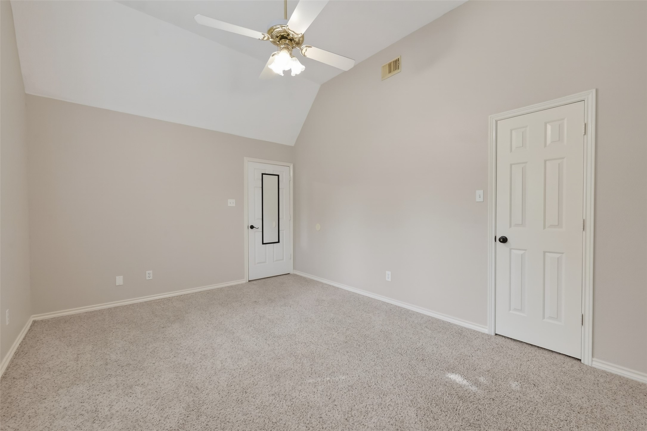 5802 Ashmere Lane Spring, TX 77379 - Photo 31 of 41 This photo shows a spacious, carpeted room with neutral-colored walls, a ceiling fan, and high ceilings. There are two white doors, providing access to adjoining areas, enhancing the room's functionality.