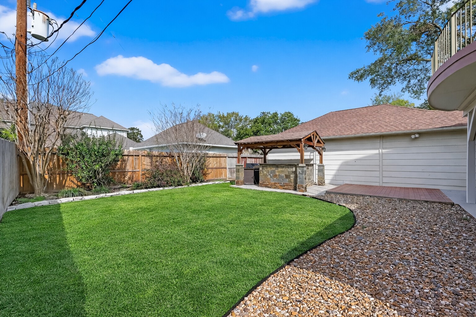 5802 Ashmere Lane Spring, TX 77379 - Photo 41 of 41 This photo shows a spacious backyard featuring a well-maintained lawn, a gravel walkway, a wooden pergola with a built-in grill area, and surrounding fencing for privacy. Perfect for outdoor entertaining and relaxation.