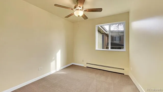 an empty room with a fan & a window