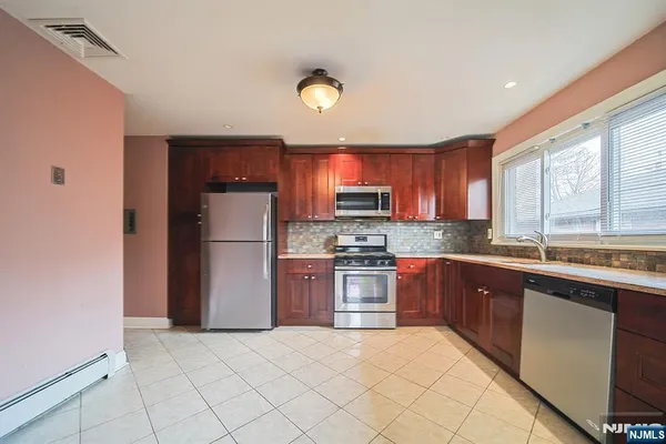 a large kitchen with stainless steel appliances granite countertop a refrigerator a sink dishwasher a stove with wooden cabinets and floor