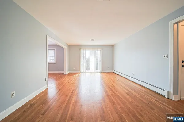 a view of an empty room with wooden floor and window