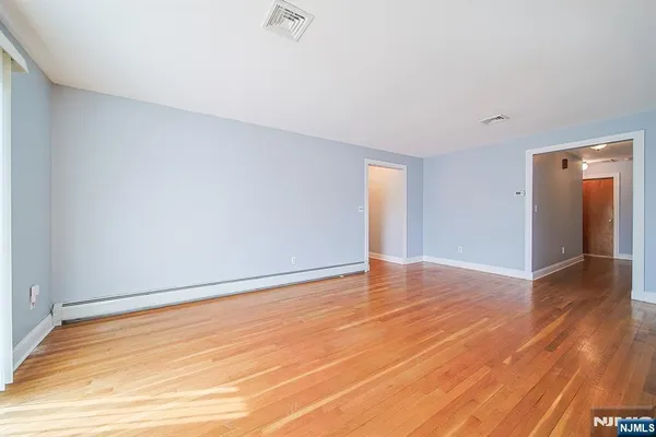 a view of an empty room with wooden floor and closet