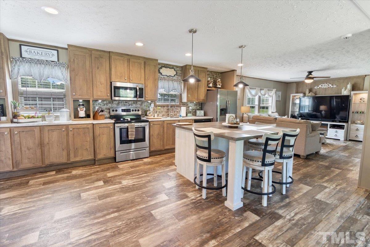 11271 Beaver Dam Road Middlesex, NC 27557 - Photo 8 of 33 a kitchen with stainless steel appliances granite countertop a stove top oven a sink dishwasher a dining table and chairs with wooden floor