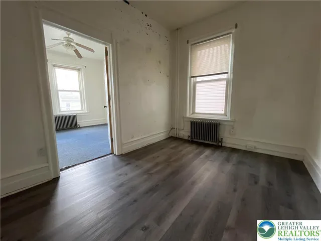an empty room with wooden floor and windows