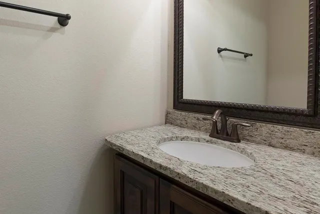a bathroom with a granite countertop sink and a mirror