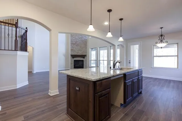 a kitchen with granite countertop a stove a sink wooden floor and a fireplace