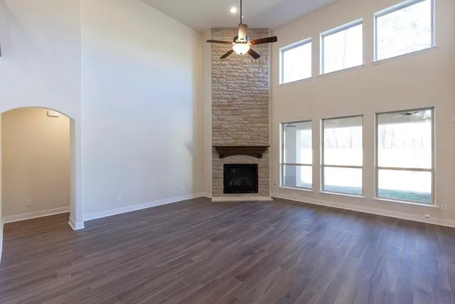 a view of an empty room with wooden floor fireplace and a window