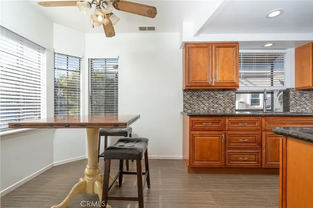 a kitchen with stainless steel appliances granite countertop wooden cabinets a dining table and chairs