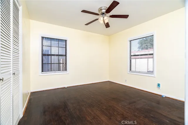 an empty room with wooden floor fan and windows