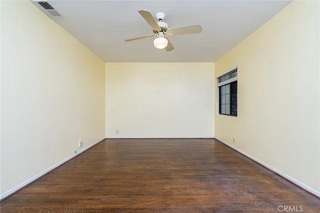 an empty room with wooden floor and ceiling fan