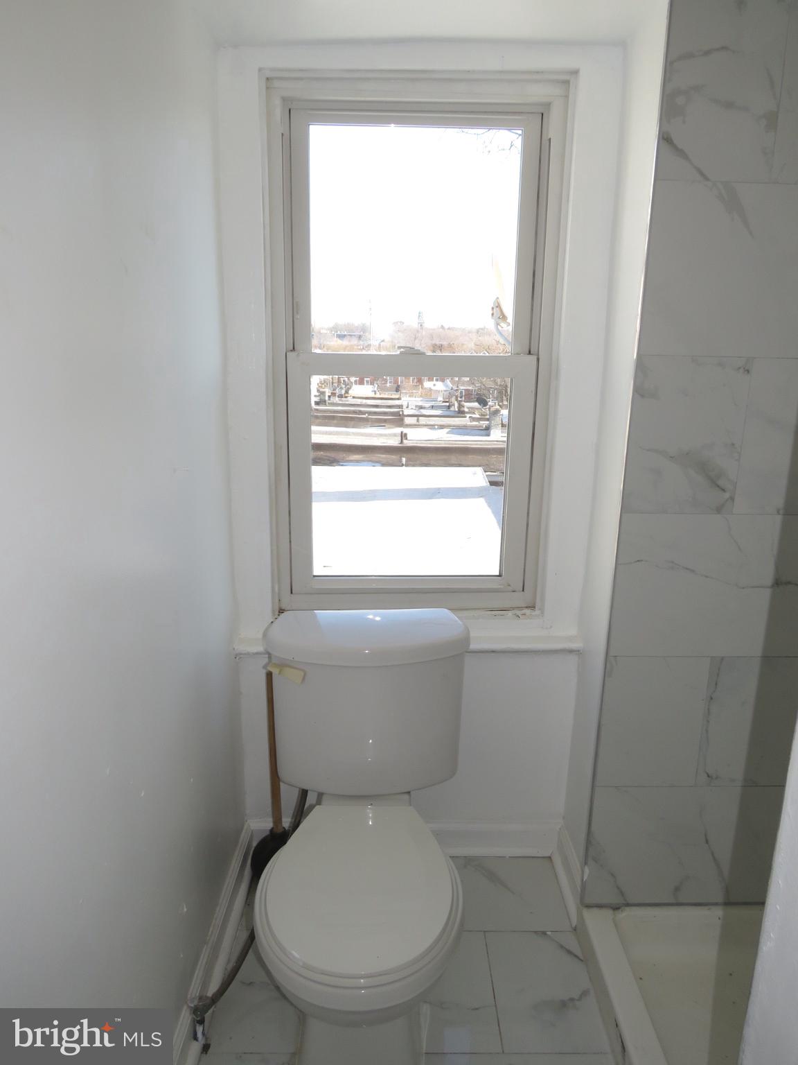 356 East Walnut Lane, Unit 3 Philadelphia, PA 19144 - Photo 11 of 18 a white toilet sitting in a bathroom next to a window