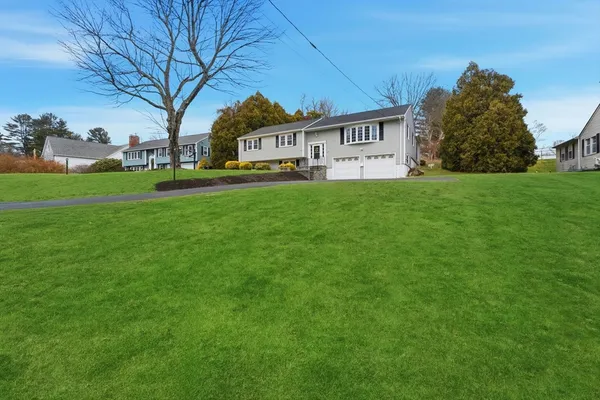 a view of house with yard and trees in the background