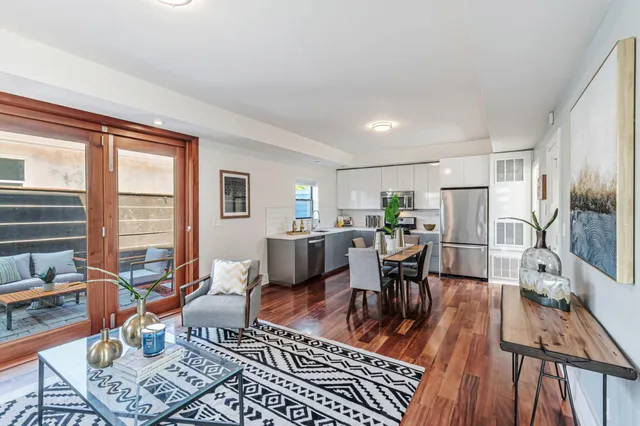 a living room with furniture a large window and wooden floor