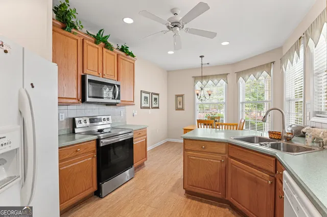 a kitchen with stainless steel appliances granite countertop a sink a stove a refrigerator cabinets and a window