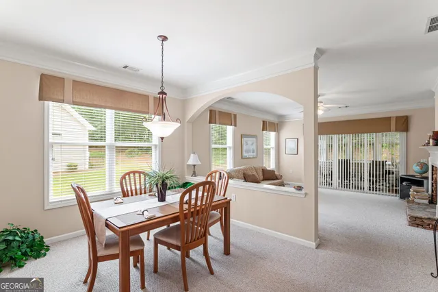 a dining room with furniture large windows and a chandelier
