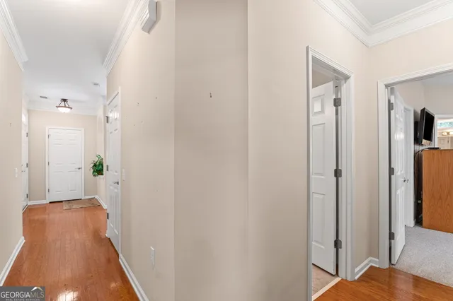 a view of a hallway with wooden floor and a bathroom