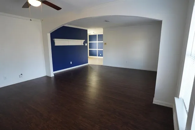 an empty room with wooden floor closet and windows