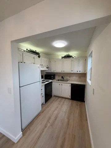 a large kitchen with a refrigerator a sink and cabinets