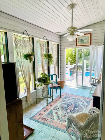 a living room with patio furniture large windows with wooden floor