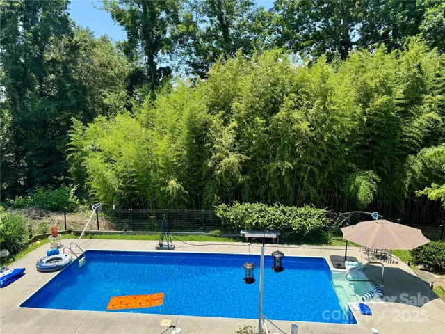 a view of swimming pool with lounge chair and trees