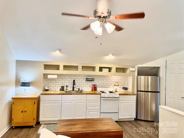 a kitchen with a refrigerator a sink cabinets and wooden floor